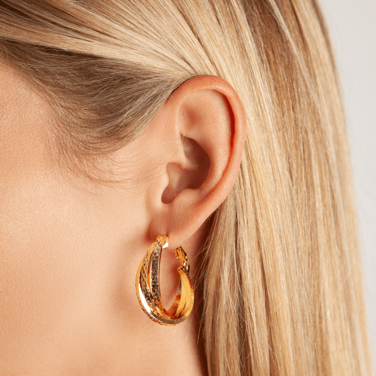 Model wearing Vivienne Twisted Hoop Earrings In Gold