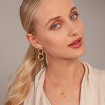 Model wearing Zaha Abstract Twisted Circles Drop Earrings in Gold