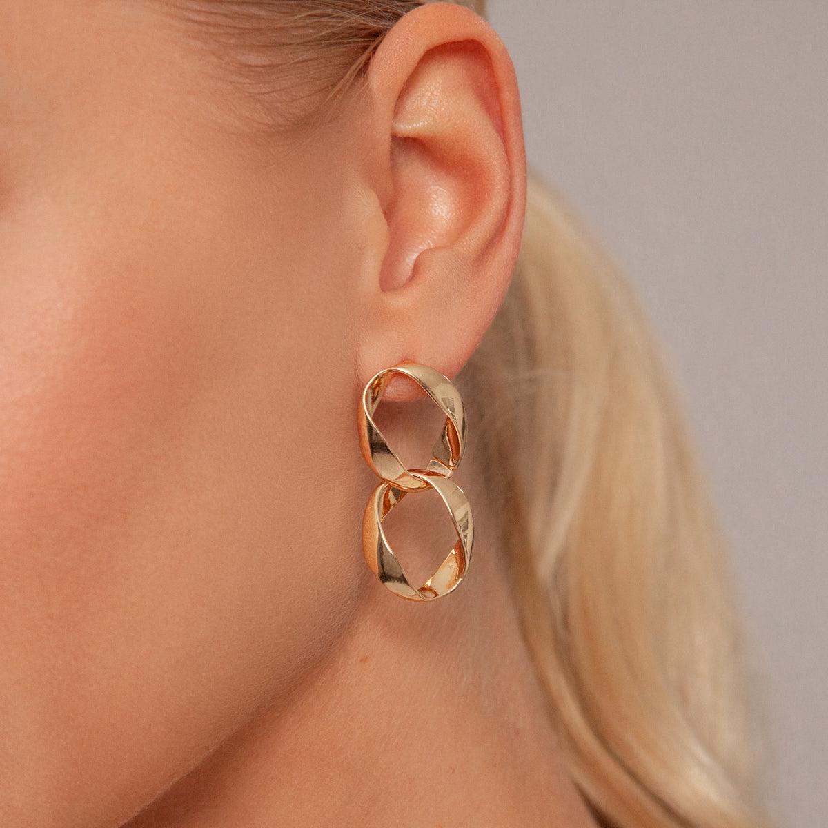 Model wearing Zaha Abstract Twisted Circles Drop Earrings in Gold