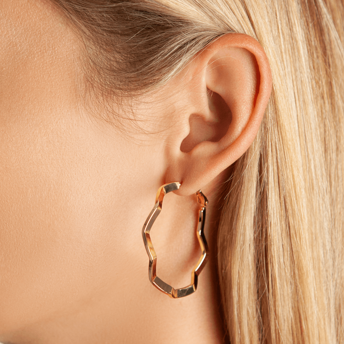 Close-up view of model wearing Eternal Abstract Hoop Earrings in Gold