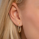 Model wearing Kylie Contemporary Crystal Hoop Earrings In Gold