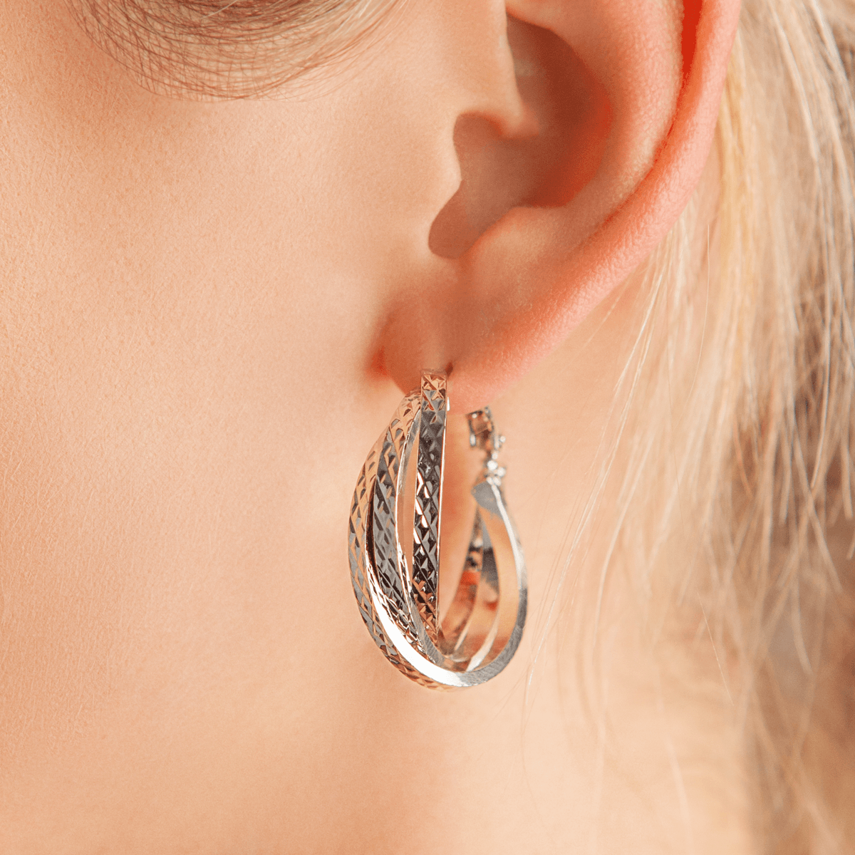Close-up view of model wearing Vivienne Twisted Hoop Earrings In White Gold